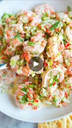 a white bowl filled with shrimp salad next to crackers