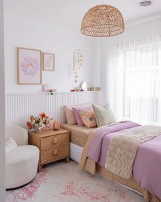 a bed room with a neatly made bed next to a chair and a lamp hanging from the ceiling