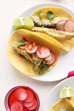 two tacos with radishes, cilantro and limes on them