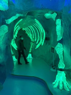 a man standing in front of a tunnel filled with fake skeleton hands and glowing green lights