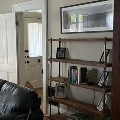 a black leather couch sitting in front of a wooden shelf filled with books and pictures