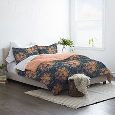 a bed in a room with a flowered comforter and pillows on the floor