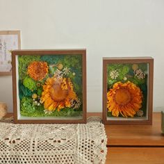 two framed pictures with flowers on them sitting on a table next to a teddy bear