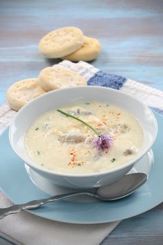 a white bowl filled with soup next to crackers on a blue and white plate