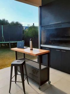 an outdoor bbq with two stools next to it