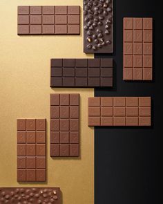 chocolate squares and pieces of chocolate are arranged on a black surface with gold foiling