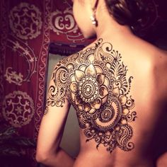 the back of a woman's body with henna tattoos on it