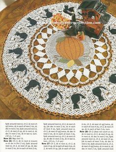 an old fashioned doily with black cats and pumpkins on it, sitting on top of a wooden table