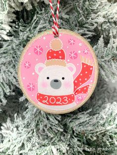 a christmas ornament hanging from a tree with snowflakes and a bear