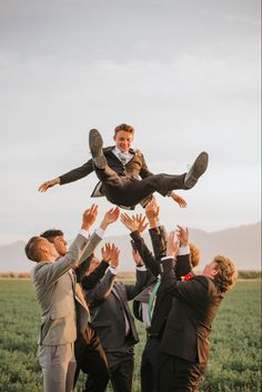 a group of people in suits and ties are holding up a man on his shoulders