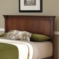 a wooden headboard with green pillows and a flat screen tv mounted above the bed