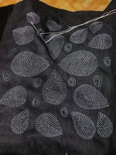 a black piece of cloth with white designs on it sitting on top of a wooden floor