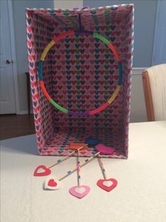 an open gift bag sitting on top of a table filled with heart shaped stickers