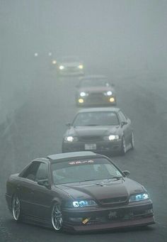 several cars driving on a road in the fog