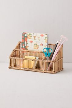 a wicker basket with scissors, books and other items in it on a white surface