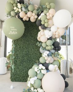 balloons and greenery are arranged in the shape of an arch for a birthday party