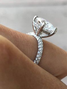 a woman's hand with a diamond ring on top of her finger and an engagement band