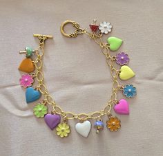 What a fun piece to wrap around your wrist!  This is a gold tone charm bracelet that boasts 7 enameled heart charms, 7 enameled flower charms, and 3 enameled 3D mushroom charms.  The chain is a gold tone soldered chain.  I've ended the piece with a horseshoe shaped gold tone toggle clasp.  This bracelet is approximately 8 to 8 1/4 inches. Cute Metal Jewelry With Heart Charm, Cute Multicolor Jewelry With Removable Charms, Heart Shaped Multicolor Charm Bracelet For Gift, Heart-shaped Multicolor Charm Bracelet For Gift, Heart-shaped Multicolor Charm Bracelet As Gift, Heart Shaped Multicolor Charm Bracelet Gift, Multicolor Heart Charm Bracelet Gift, Multicolor Heart Charm Bracelet, Multicolor Enamel Heart-shaped Jewelry