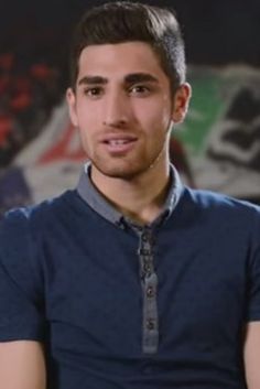 a young man sitting in front of a wall with graffiti on it's walls