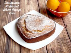 a heart shaped cake sitting on top of a white plate next to oranges in a bowl