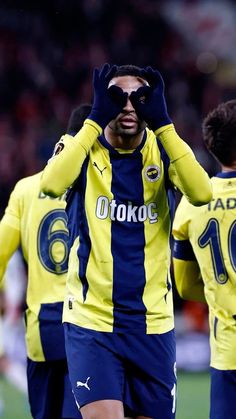 a soccer player is covering his eyes with his hands as he walks on the field