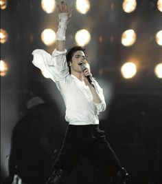 the singer is performing on stage with his arms in the air as he holds his hands up