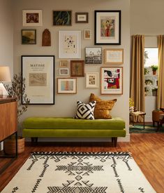 a living room filled with lots of framed pictures on the wall above a green couch