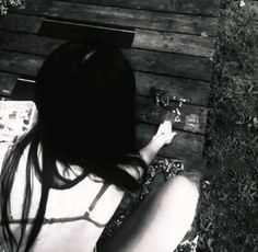 a woman sitting on top of a wooden bench