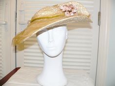 This is a vintage light straw hat. My guess is around 1930's. The brim is covered with tan/ gold tulle netting covering all of the straw with an olive green velvet ribbon and bow trim around the crown. On the back side where the brim is upturned the netting is folded up over it with 2 sets of pale pink velvet flowers with pale blue stamens. The hat was pictured with the straight stitches inside the front of the brim to the front and tilted. It could be worn several different ways. Inside is the Gold Brimmed Straw Hat For Kentucky Derby, Vintage Brimmed Sun Hat For Wedding, Vintage Beige Straw Hat For Wedding, Vintage Beige Straw Hat For Weddings, Vintage Gold Hat For Kentucky Derby, Gold Hats With Short Brim For Garden Party, Vintage Gold Wide Brim Hat, Gold Wide Brim Vintage Hat, Gold Vintage Hats For Vintage Events