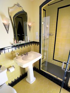 a bathroom with yellow and black tiles on the floor, sink, toilet and shower stall