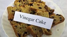 a white plate topped with slices of cake next to a sign that reads vinegar cake