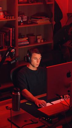 a man sitting in front of a computer with headphones on and looking at the screen