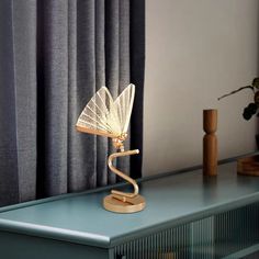 a table with a lamp on top of it next to a blue cabinet and curtains