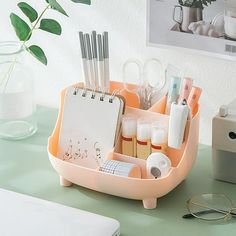 an orange desk organizer with pens, pencils and eyeglasses in it on a green table