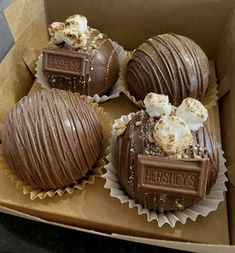 four chocolate covered desserts sitting in a box