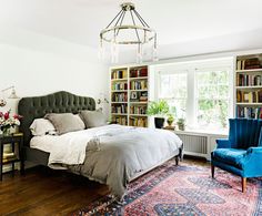 a bedroom with a bed, chair and bookshelf