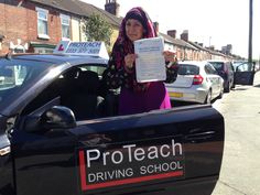 a woman standing in the back of a black car holding up a piece of paper