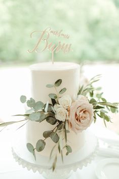 a wedding cake with flowers and greenery on top