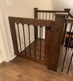 an open wooden gate in the middle of a room with hardwood floors and white walls