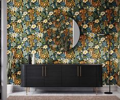 a black cabinet and mirror in front of a floral wallpaper