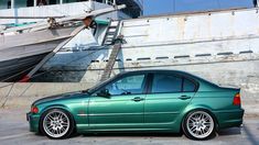 a green car parked in front of a boat