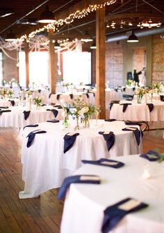 tables with white and blue linens are set up for a formal function at the venue