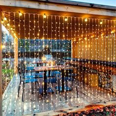 an outdoor dining area with string lights strung across the ceiling and patio furniture on the deck