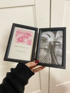 a person holding up two framed pictures with writing on them