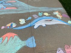 the sidewalk is painted with chalk and has different colored drawings on it, including dolphins