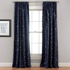 the curtains are hanging in front of the window with stars on them and one light is turned on