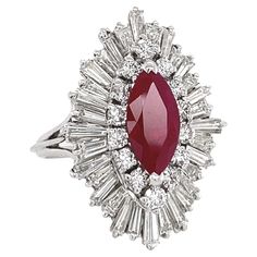 This classic ballerina ring -- with baguettes of various sizes forming a "skirt" at different elevations -- was originally set with a diamond, but we decided to set it with something more wearable and contemporary -- a maroon ruby -- nearly opaque and completely saturated with rich color. The 1.78 carat mixed cut ruby, from Mozambique (heat-treated but not filled) has a shallow crown, so that it appears almost flat. The ruby is surrounded by a 1/2 carat of round stones - a diamond halo of 14 round, full-cut stones that we rate at G-H color and VS2-SI1 clarity. The 32 baguettes - we estimate 2 carats worth - are all tapered, ranging from 3mm and 4mm in length. We rate the baguettes at H color and VS1-2 clarity. All stones are securely prong-set. At least two of the baguettes appear to be re Ballerina Ring, The Ring Face, Cluster Ring, Mozambique, Cocktail Rings, Halo Diamond, White Diamond, Diamond White, Prong Setting