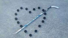 a hockey stick and some black balls on the ice with it's name written in white