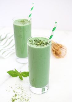 two glasses filled with green smoothie on top of a table