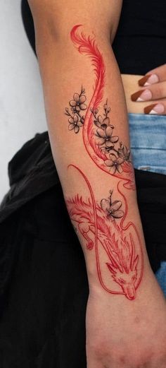 a woman's arm with a red dragon tattoo on it